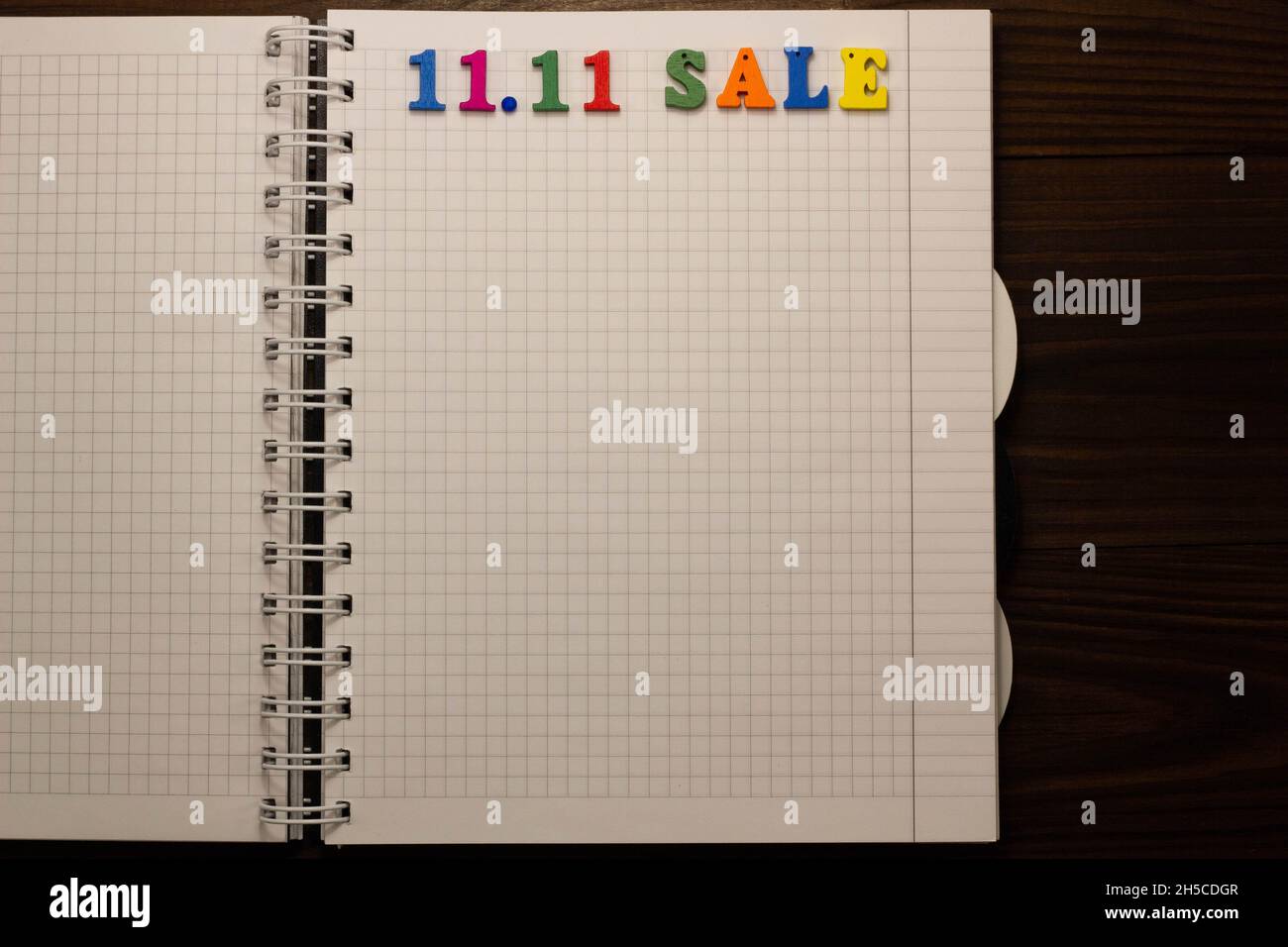 11.11 Sale concept. Multicolored colorful letters in a squared exercise book on the table with copy space for text. Shopping list. Mega Shopping Day. Stock Photo