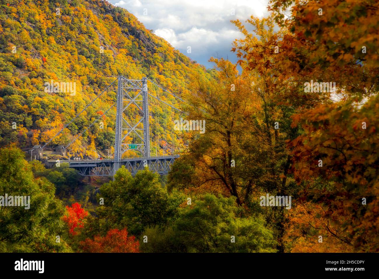 Bear Mountain Bridge Fall  - Looking south at Bear Mountain Bridge, and the Amrican flag draped over one of the stanchions during autumn with its magn Stock Photo