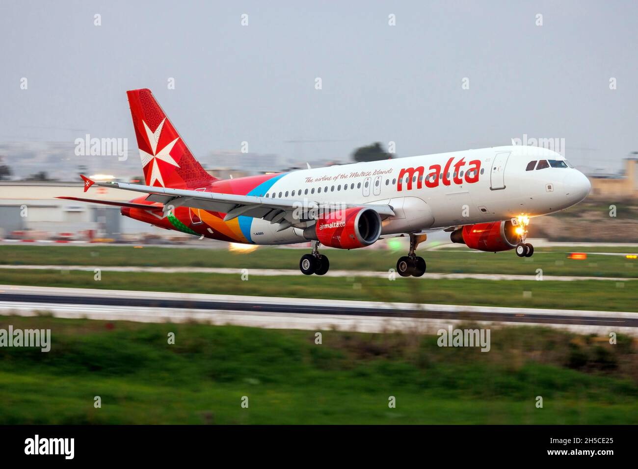 Air Malta Airbus A320-214 (REG: 9H-AEQ) landing runway 13 after sunset. Stock Photo