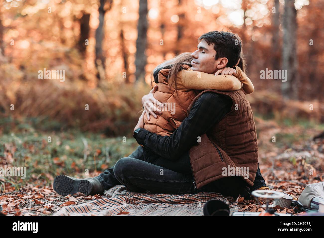 Young, romantic couple in tight embrace in the woods. Autumn time ...