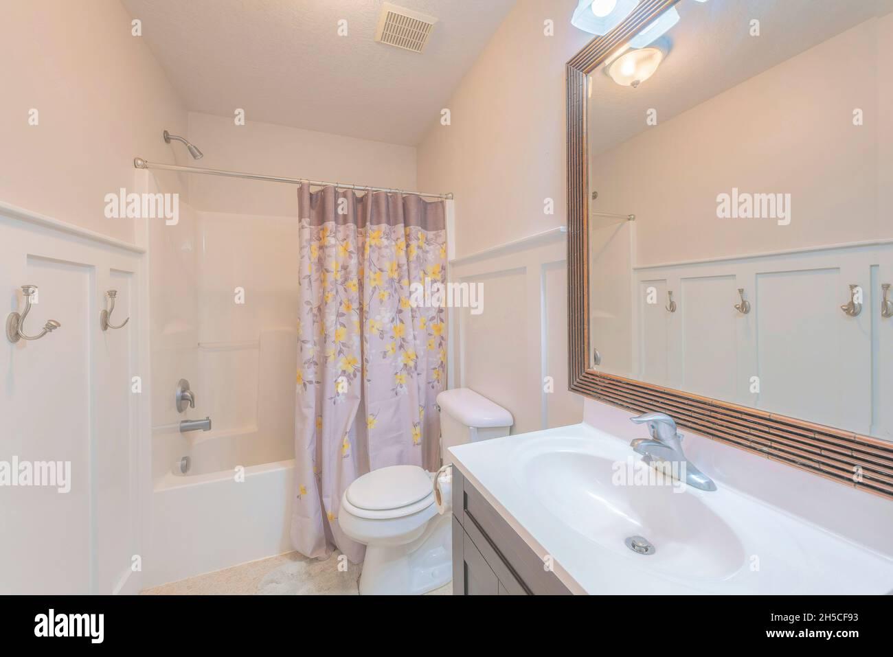 Small windowless bathroom interior with halfpaneled wall and floral