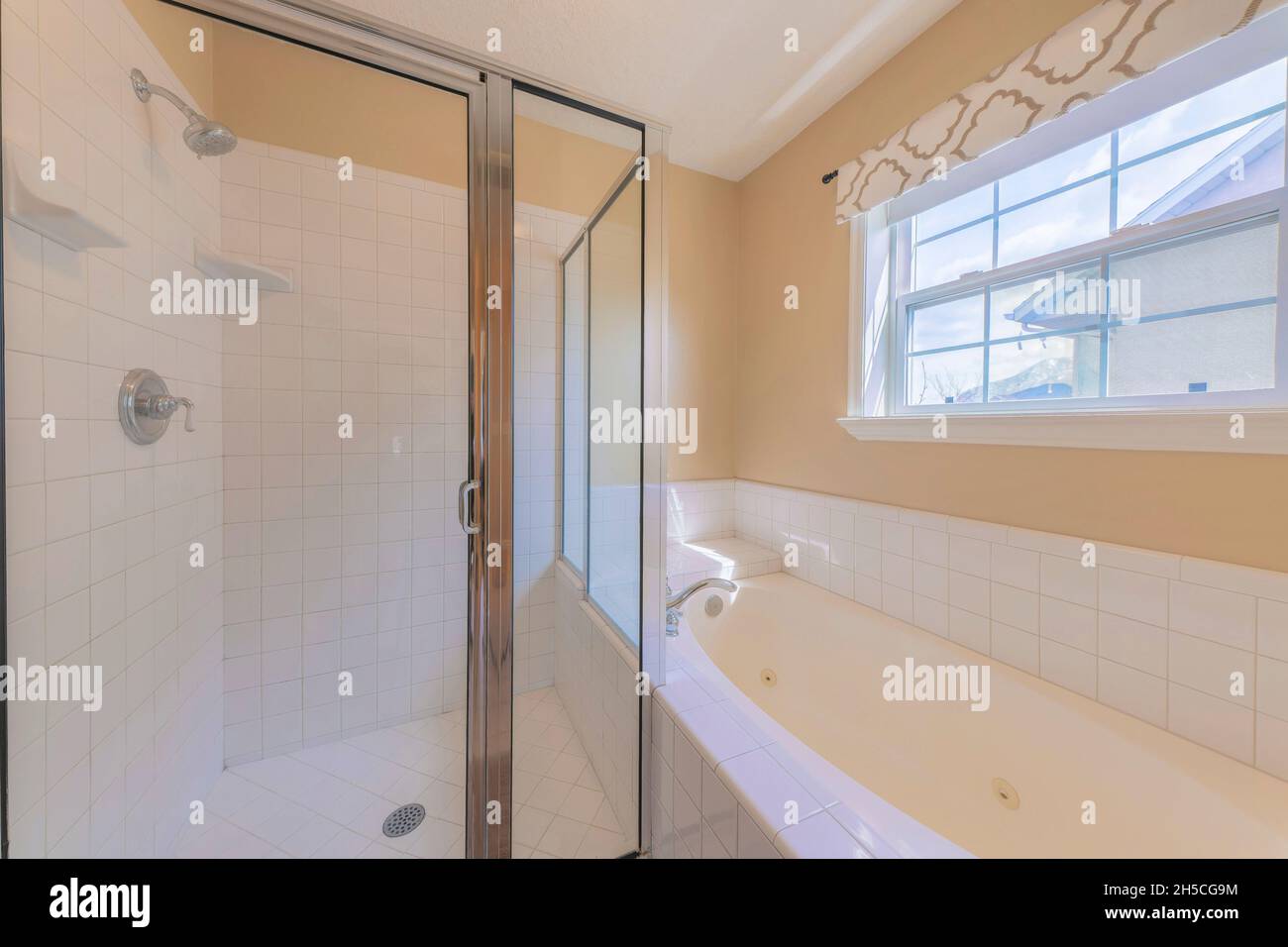 Glass shower stall and bathtub with white tiles surround Stock Photo