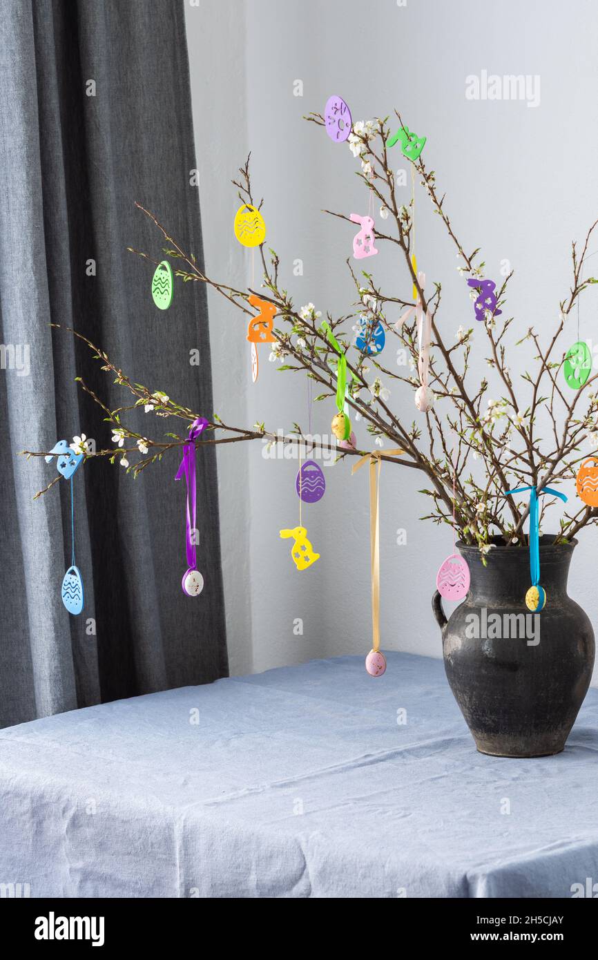 Blooming cherry branches decorated with colorful ribbons with easter eggs, Happy Easter, table setting Stock Photo