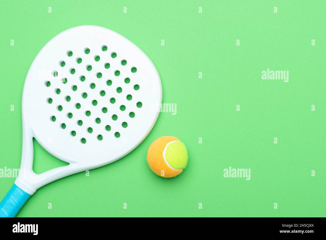 White professional paddle tennis racket and ball on green background. Horizontal sport theme poster, greeting cards, headers, website and app Stock Photo