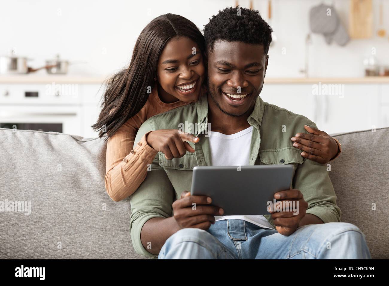 Cheerful african american couple having fun at home, using pad Stock ...