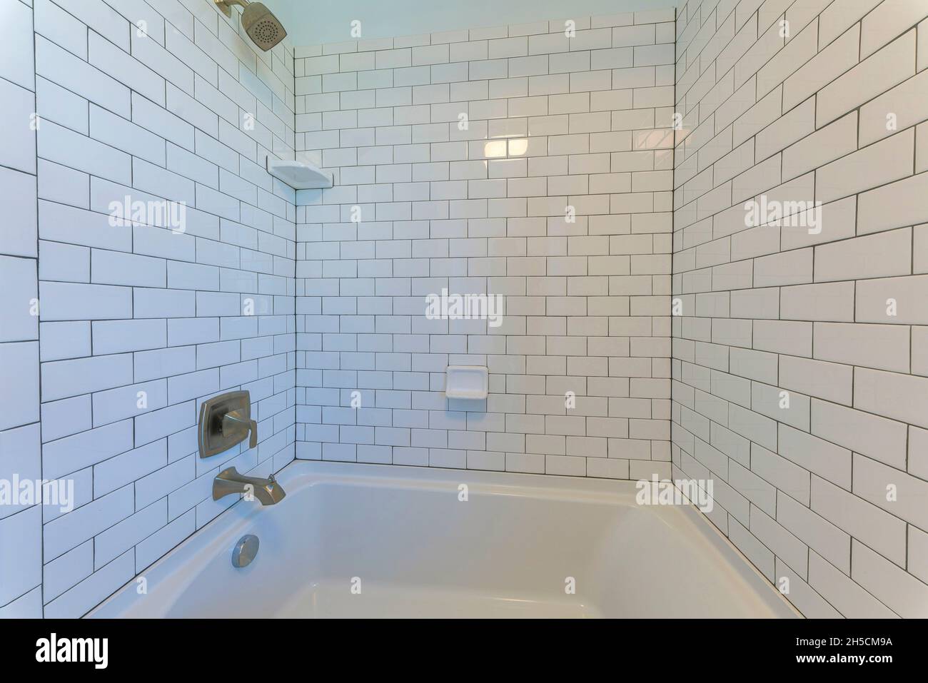 Alcove bathtub with white subway tile surround with black grout Stock