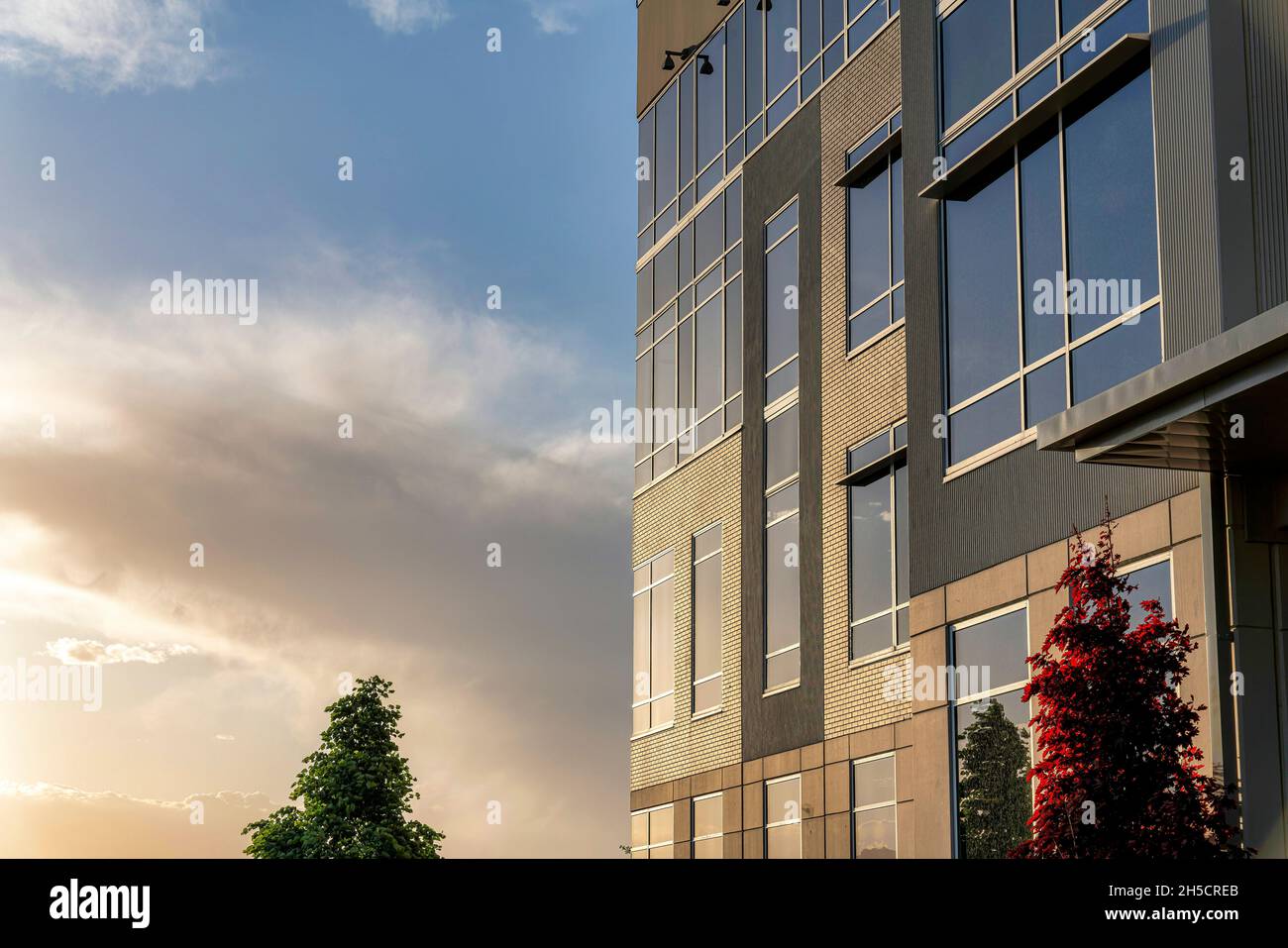 Building facade with bricks, glass and concrete wall cladding during sunset Stock Photo