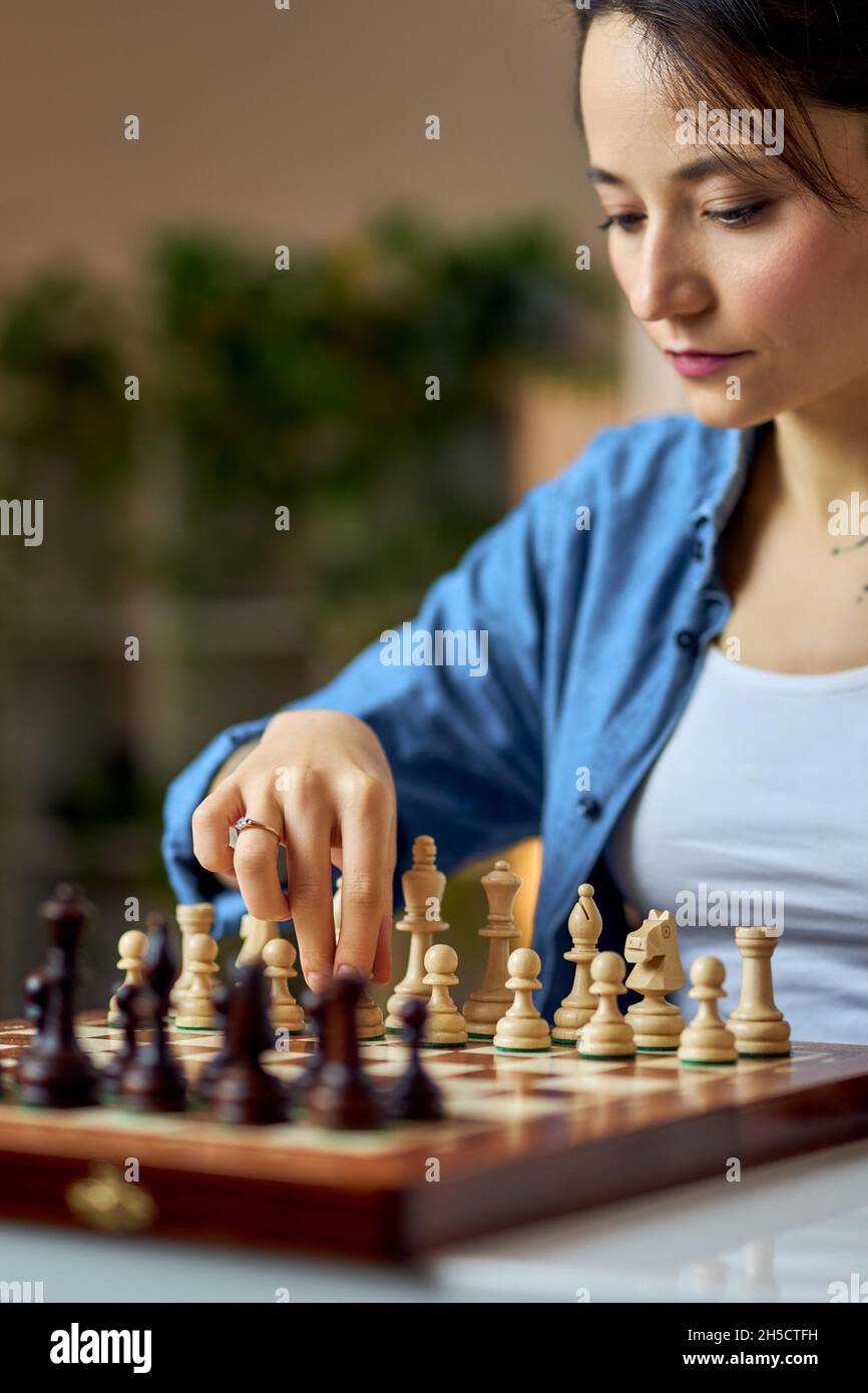 Young woman moving chess pieces on the board while playing chess game ...