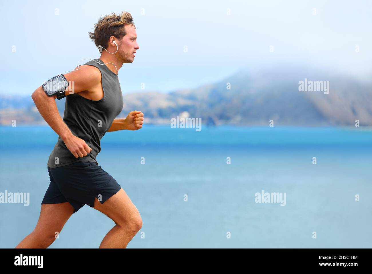 Running app on smartphone. Male runner listening to music jogging with  armband for smart phone. Fit man fitness model working outdoor by water  Stock Photo - Alamy