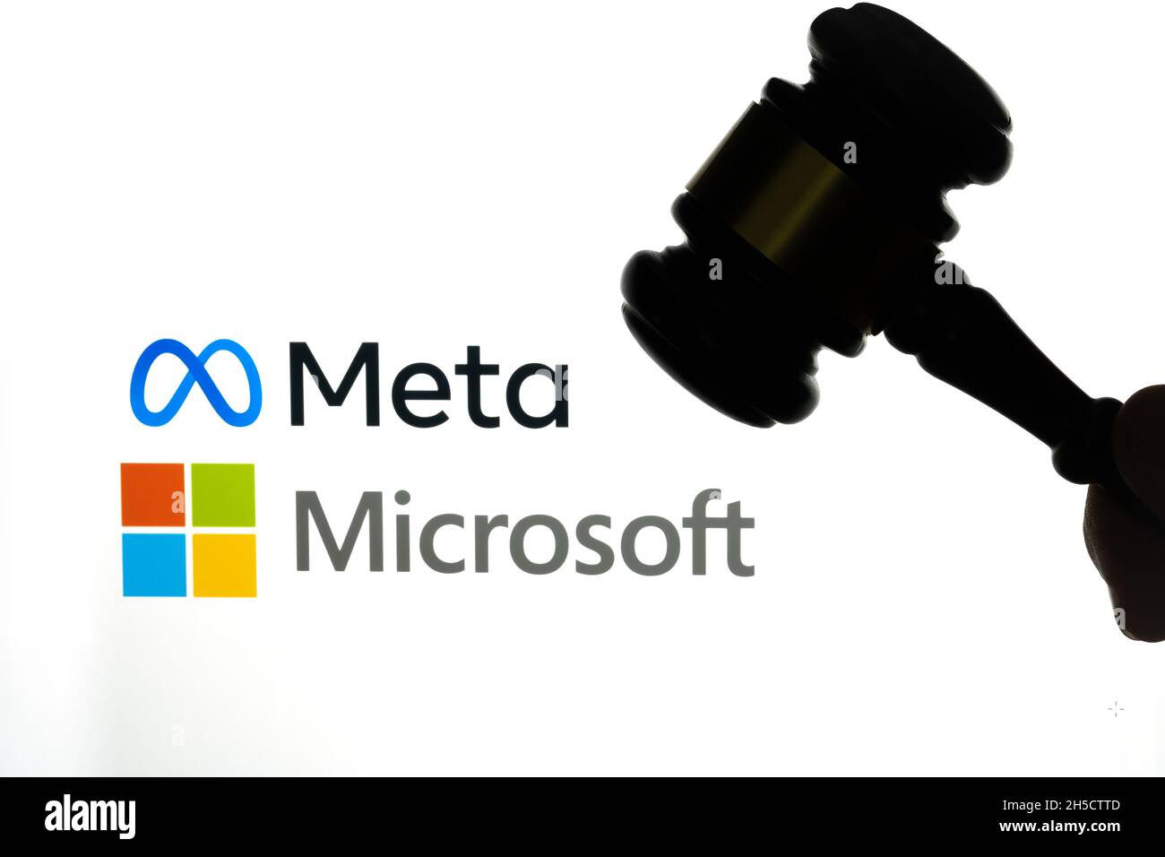 Silhouette of judges gavel in front with blurred FACEBOOK META and MICROSOFT company logos seen on laptop screen behind. Selective focus. Stafford, Un Stock Photo