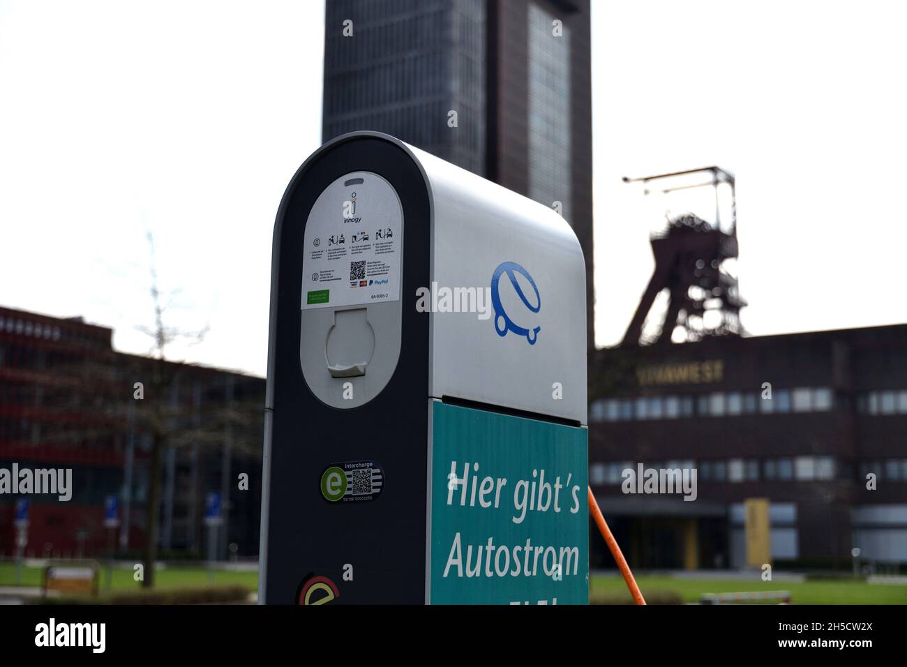 Electric charging station with winding tower in the background, Germany, North Rhine-Westphalia, Ruhr Area, Gelsenkirchen Stock Photo