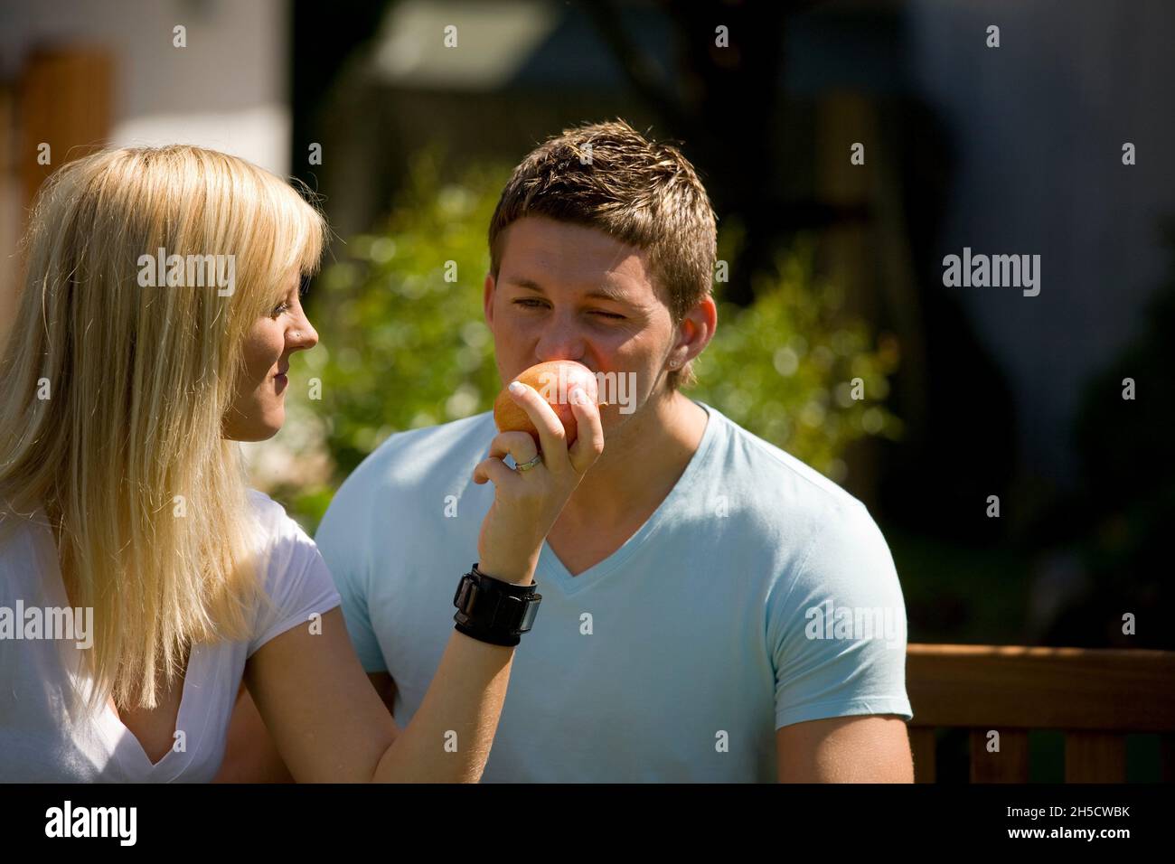 young couple in love, young woman lets her partner bite off an apple Stock Photo