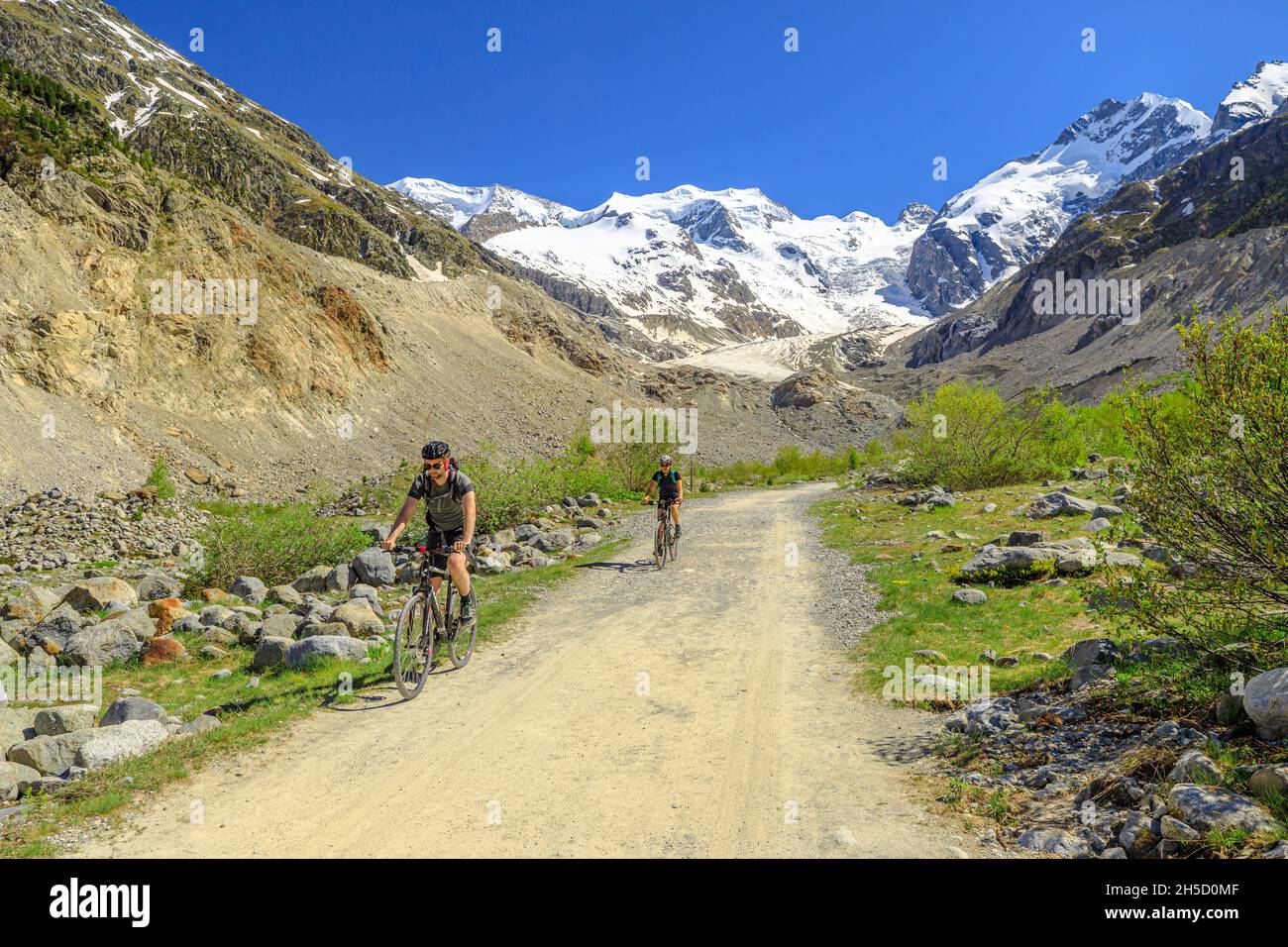 Grisons, Switzerland - June 2021: bikers by mountain bike on the trekking trail to Morteratsch glacier of Switzerland. Biggest glacier in Bernina Stock Photo