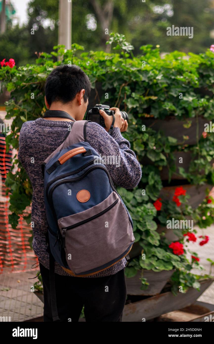 Peruvian Young-man wearing a backpack taking a picture with his profesional camera Stock Photo