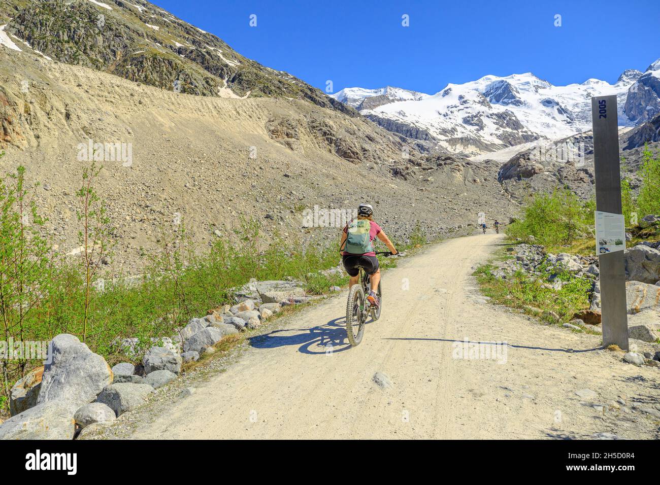 Grisons, Switzerland - June 2021: biker by mountain bike on the trail to Morteratsch glacier of Switzerland. Biggest glacier in Bernina Range of the Stock Photo