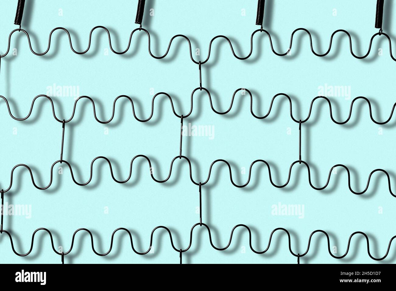 Metal zig zag springs of a folding bed isolated on light blue background Stock Photo