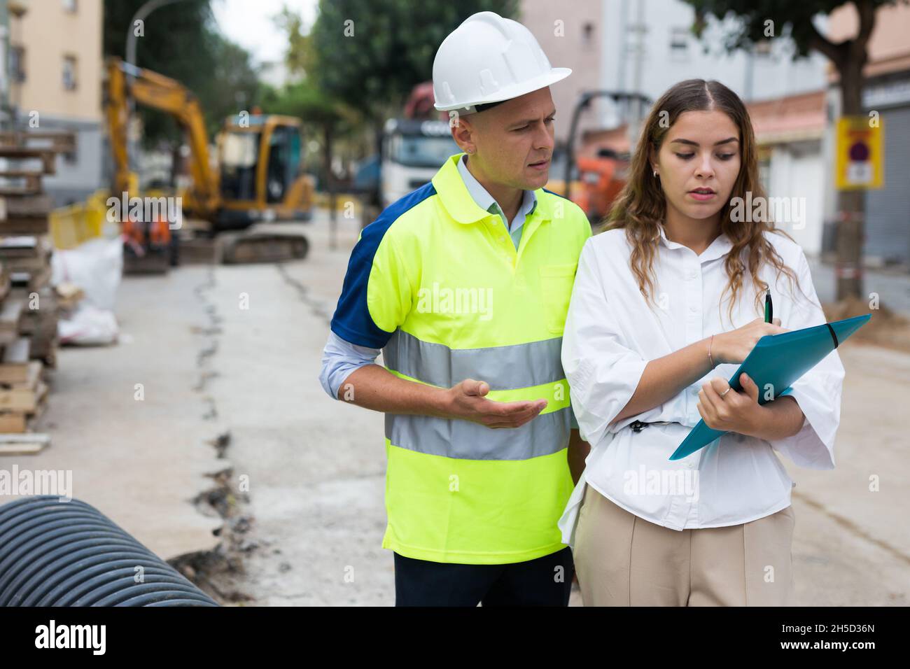Man engineer and a young woman discuss a construction project while , taking important notes Stock Photo