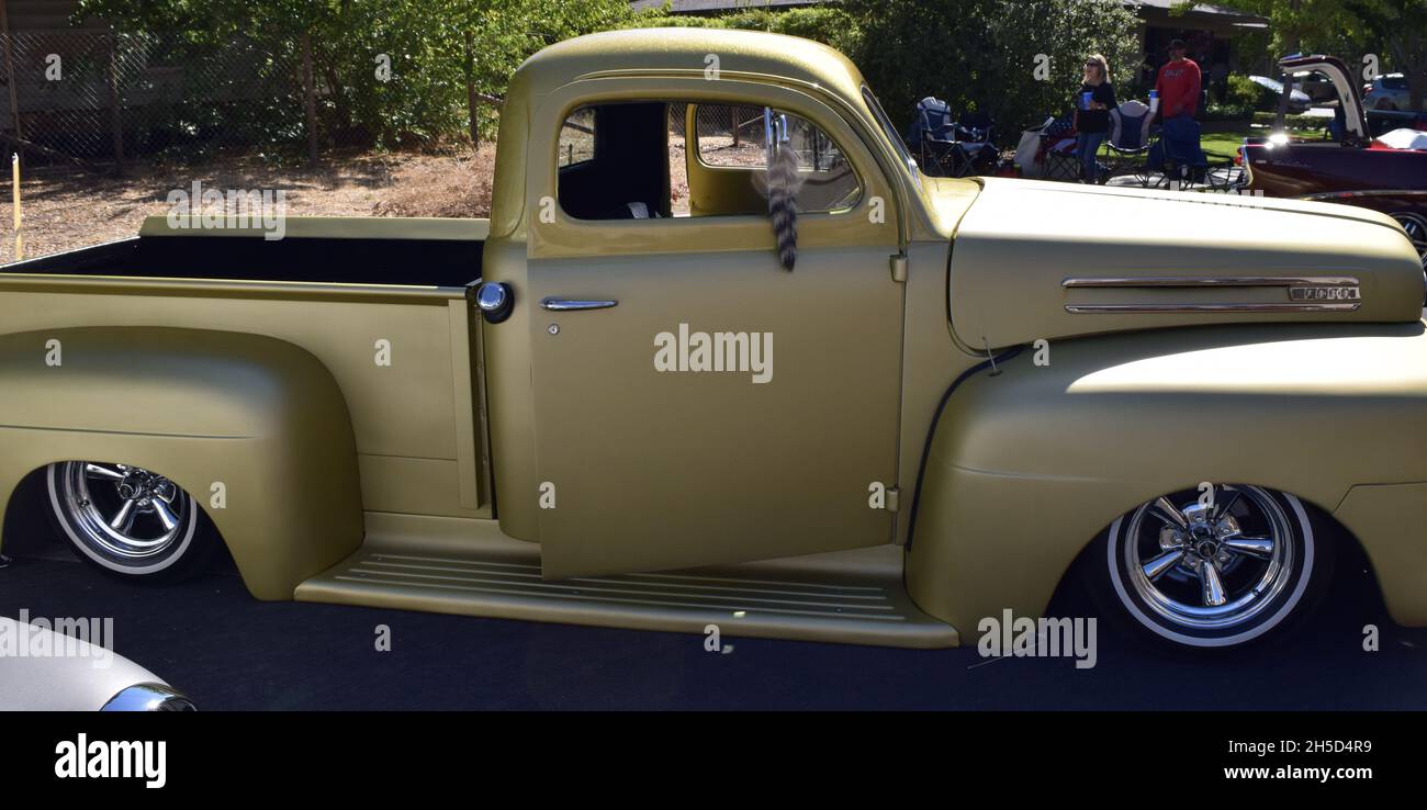 FRESNO, UNITED STATES - Oct 09, 2021: A side view photo of a gold custom designed 1950 Chevy Ford Truck Model F1 parked outside by trees at a car show Stock Photo