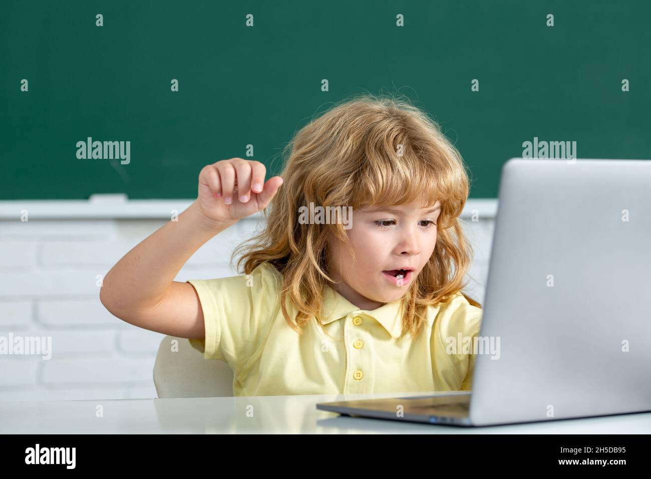 School child using digital pc laptop in class. Portrait of funny pupil of primary school study programming. Online learning technology, virtual Stock Photo