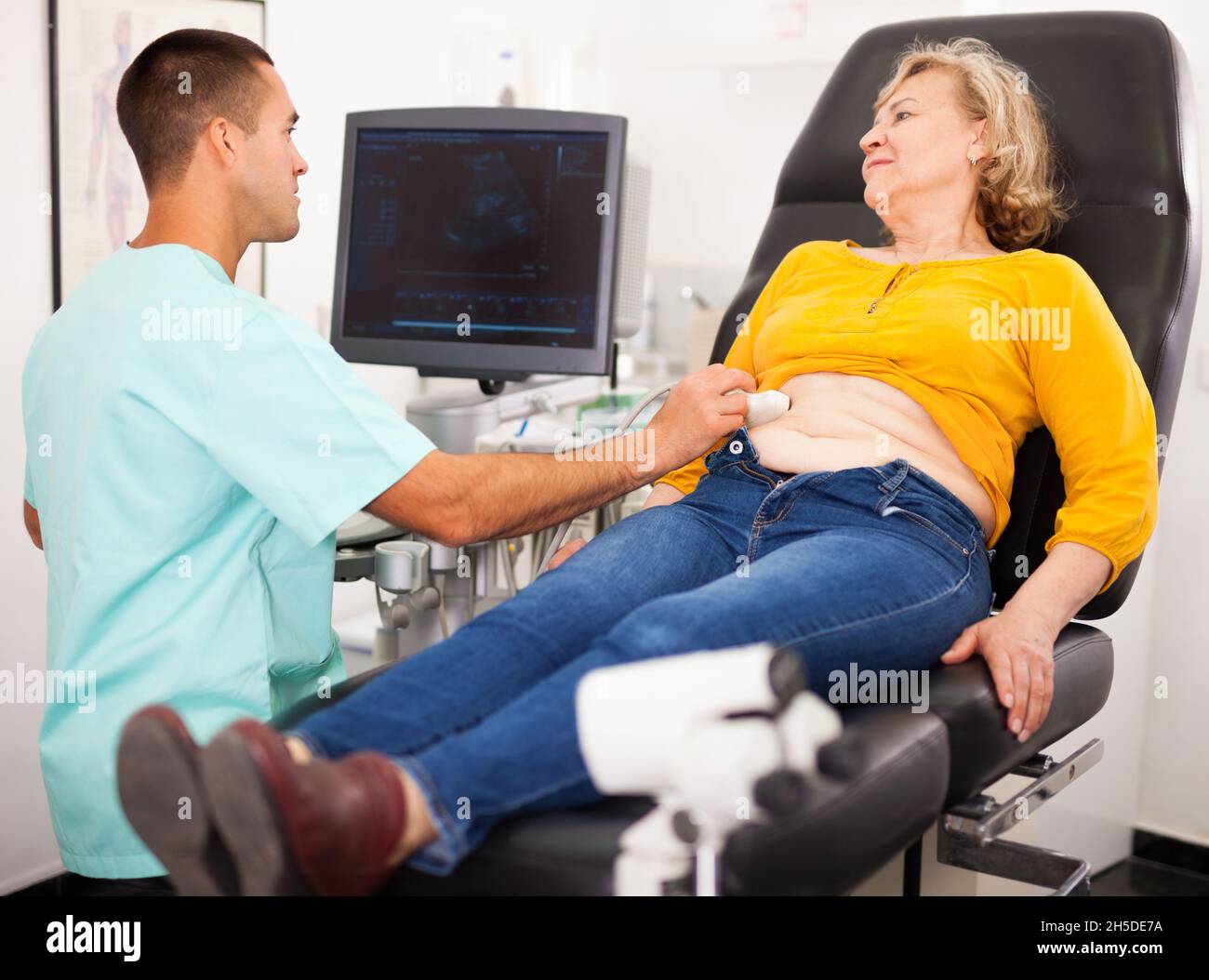 Positive male doctor diagnosing female patient using modern ultrasound ...