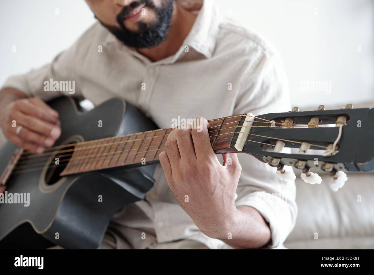 Cropped image of bearded man playing guitar and singing a song Stock Photo