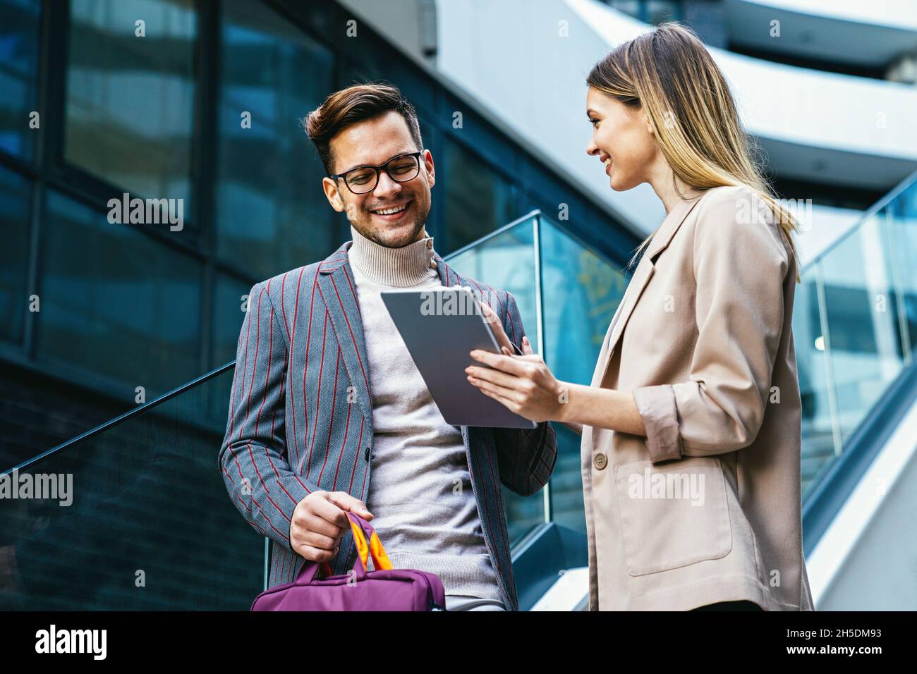 Successful young business people talking, working together in front of modern business building Stock Photo