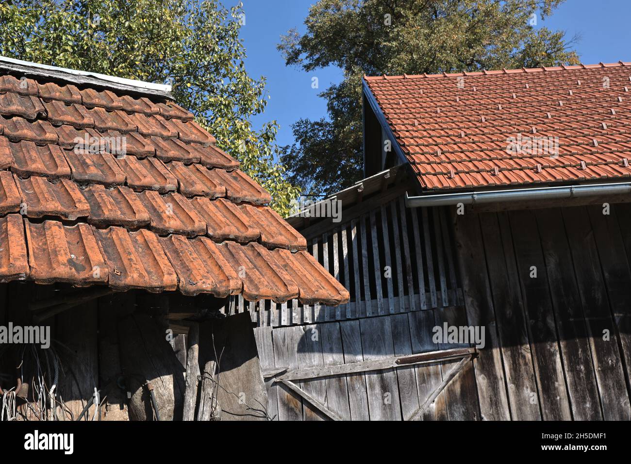 Roofs with old and new shingles on a woody building Stock Photo