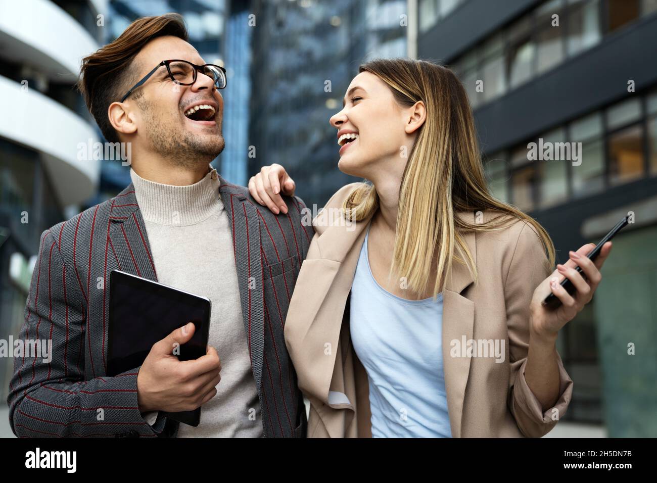 Successful young business people talking, working together in front of modern business building Stock Photo