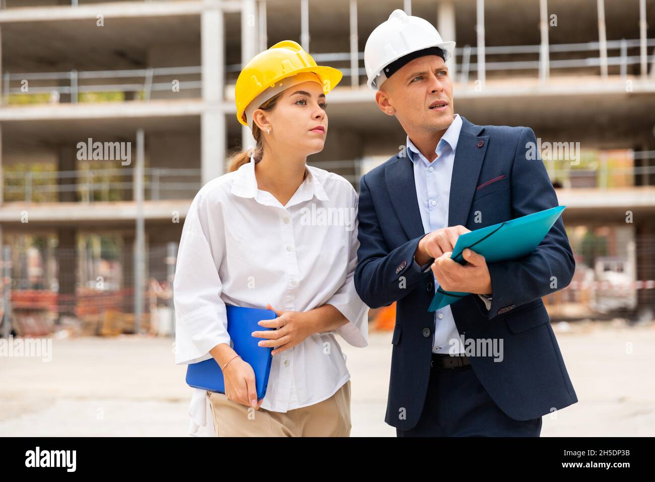 Two young successful architects on the construction site, discuss the construction plan Stock Photo