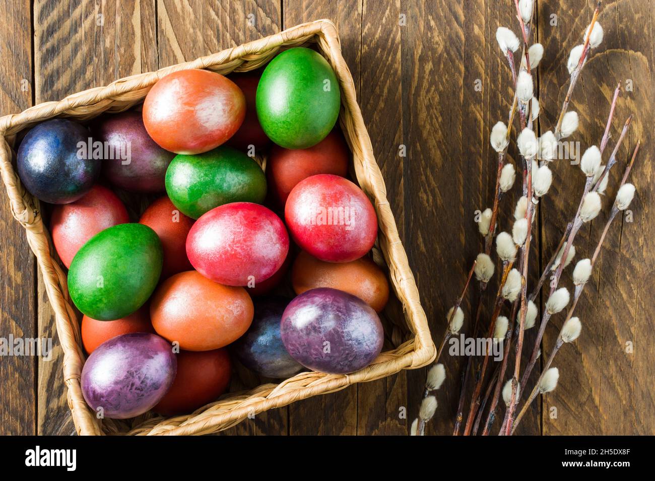 view from above of a wooden box with Easter colorful eggs and willow twigs. the concept of celebrating Easter Stock Photo