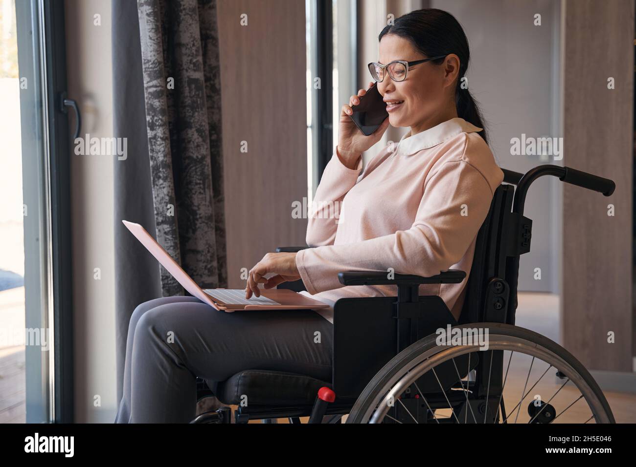 Happy mature woman with disability making call indoors Stock Photo - Alamy