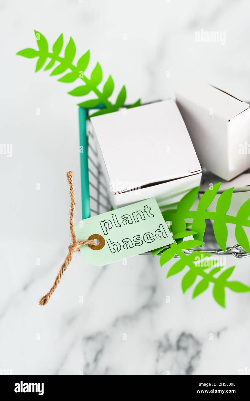 sustainability and cruelty free product concept, shopping basket with blank product packagings and green leaves with Plant-based label on them Stock Photo