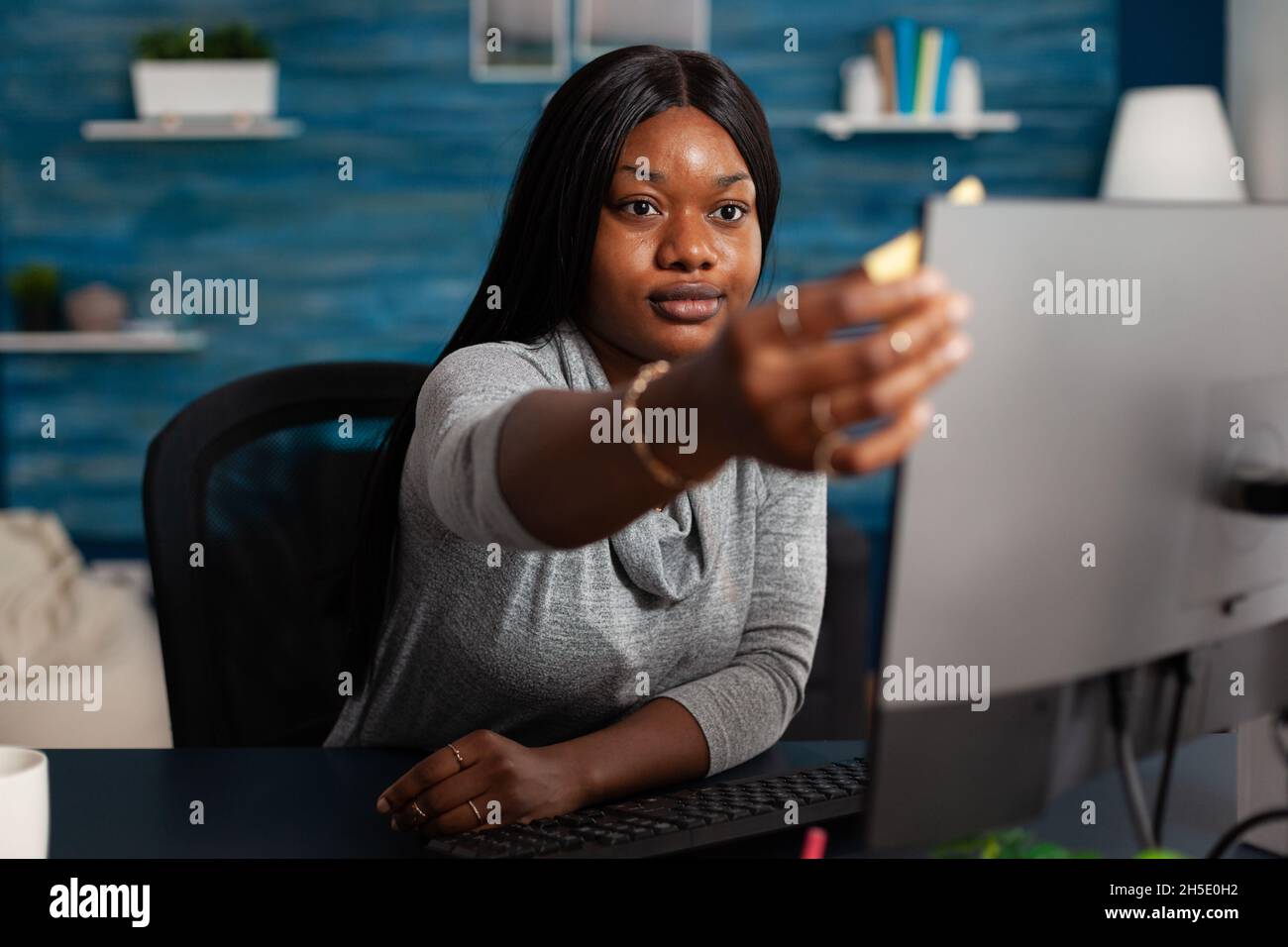 Adult putting sticky notes on monitor to work remotely. Young person using postit paper on computer to help with business project while working from home. Woman with adhesive note memo Stock Photo