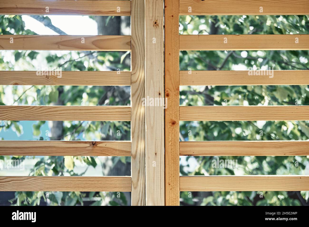 Stylish decorative partition made of thin wooden planks stands on contemporary country house terrace on spring day closeup Stock Photo