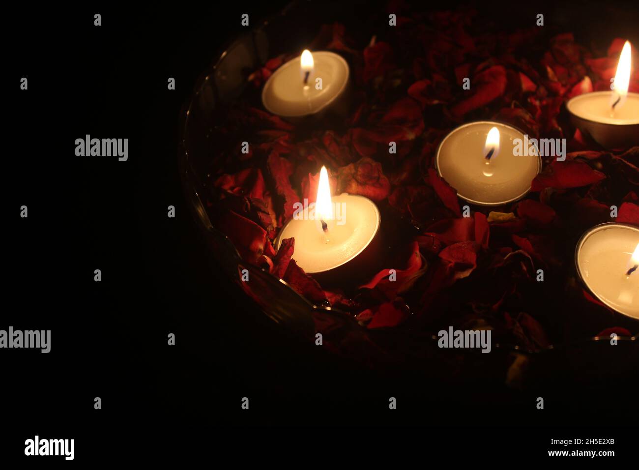 Tea light candles and red rose petals in a bowl filled with water Stock