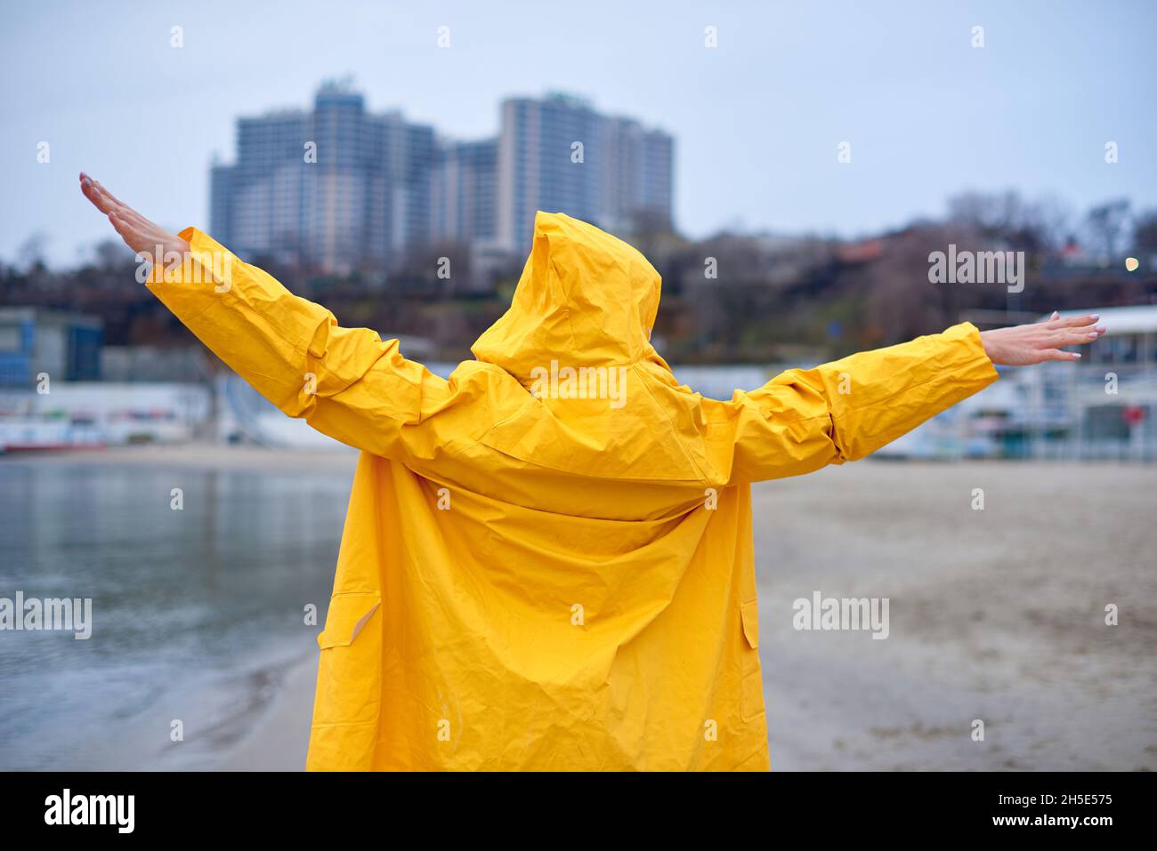 woman enjoying a winter day on the beach. Joyful woman standing on cold winter's beach with her arms outstretched and happily breathing in the fresh s Stock Photo