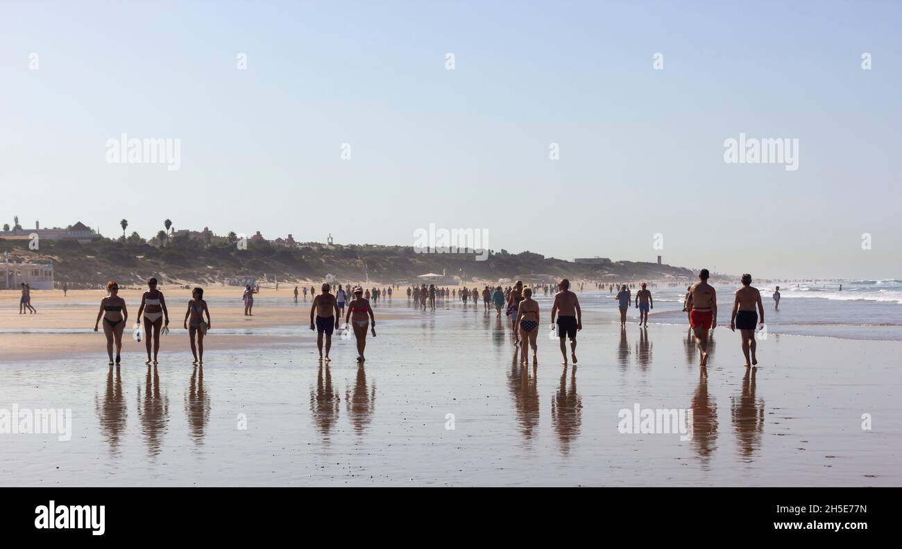 Early morning walkers on La Barrosa beach, Sancti Petri, Chiclana de la Frontera, Cadiz, Andalusia, Spain. Stock Photo