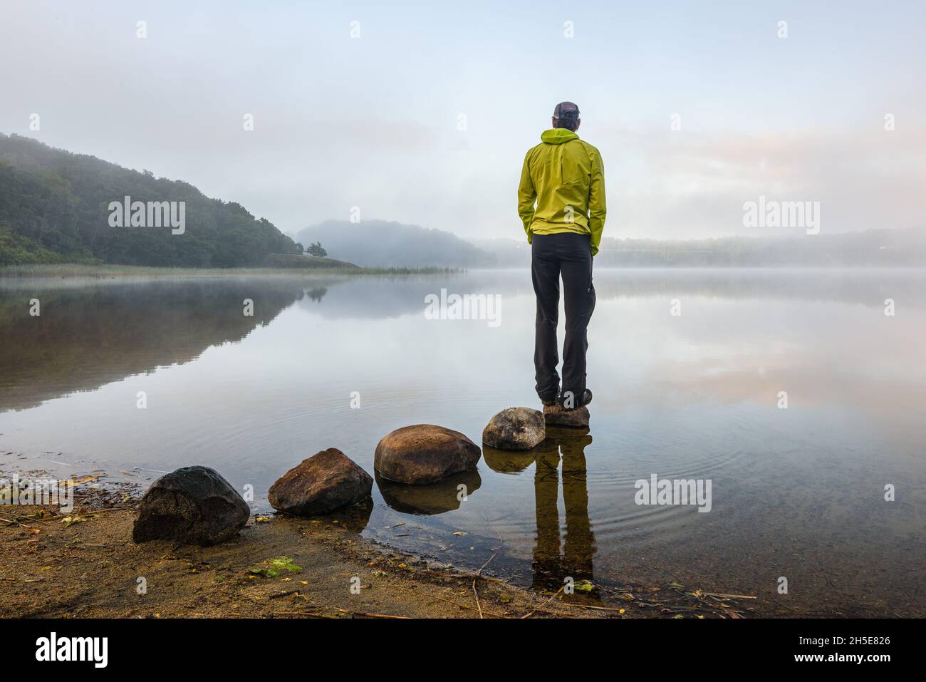 Lonely man standing at misty lake Stock Photo