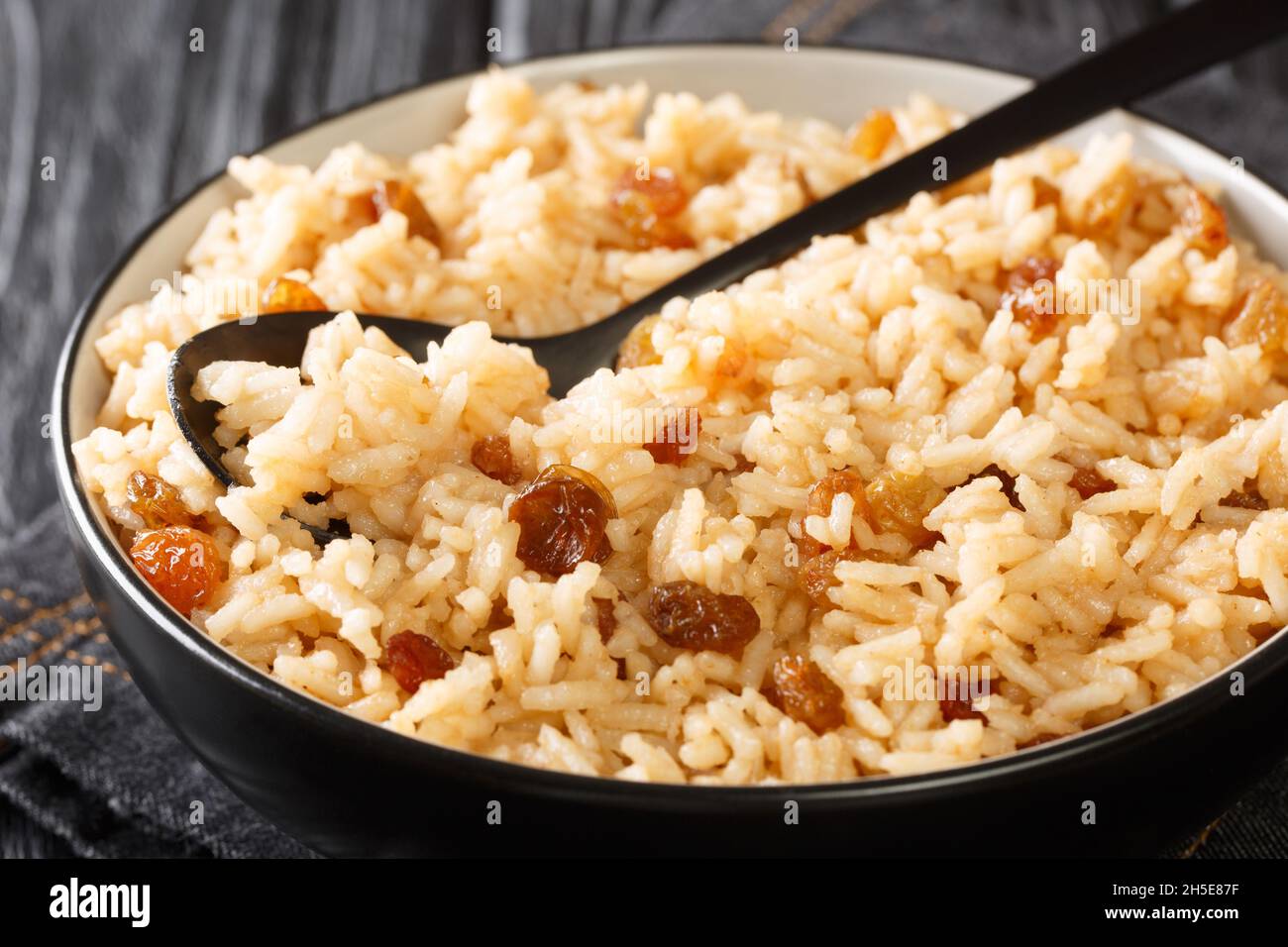 Arroz con coco is a flavorful Colombian side dish consisting of rice, coconut, sugar, salt, and raisins close-up in a bowl on the table. horizontal Stock Photo