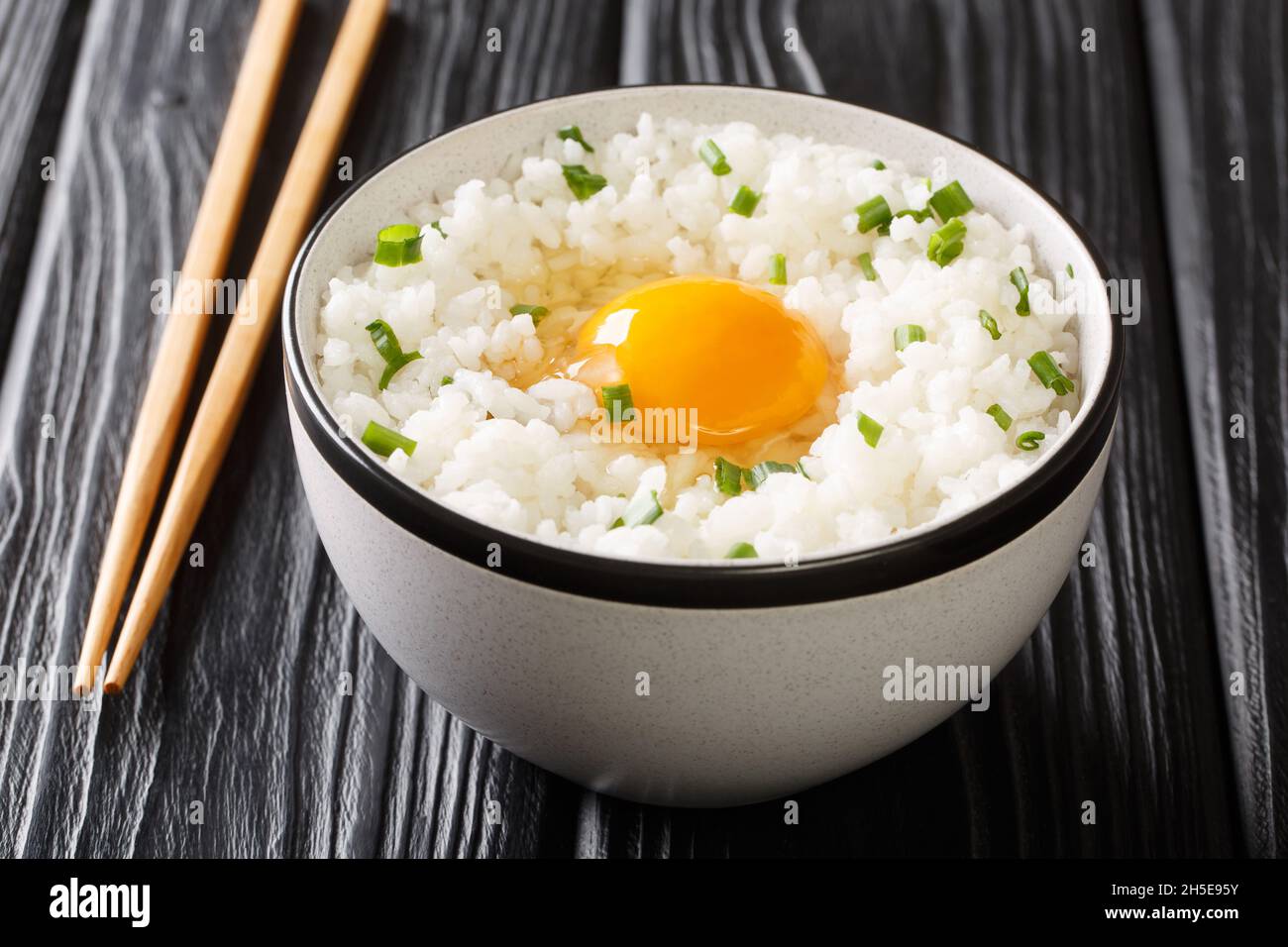 Japanese breakfast Tamago kake gohan rice topped with egg close up in the bowl on the table. Horizontal Stock Photo