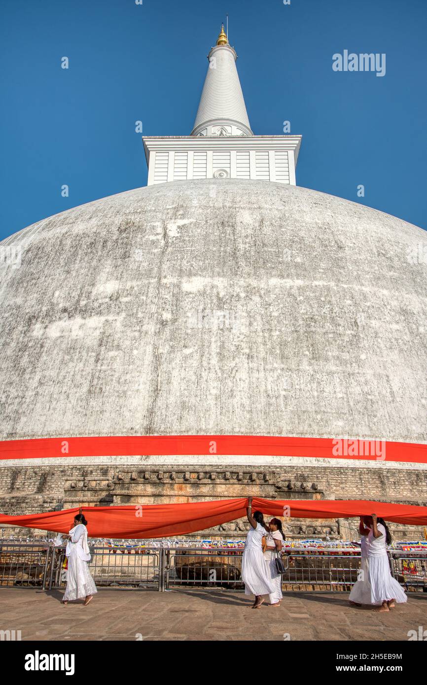 Anuradhapura, Sri Lanka - 13th January 2020: At a special ceremony an orange ribbon is wrapped around the Ruwanwelisaya Stupa by a procession of peopl Stock Photo