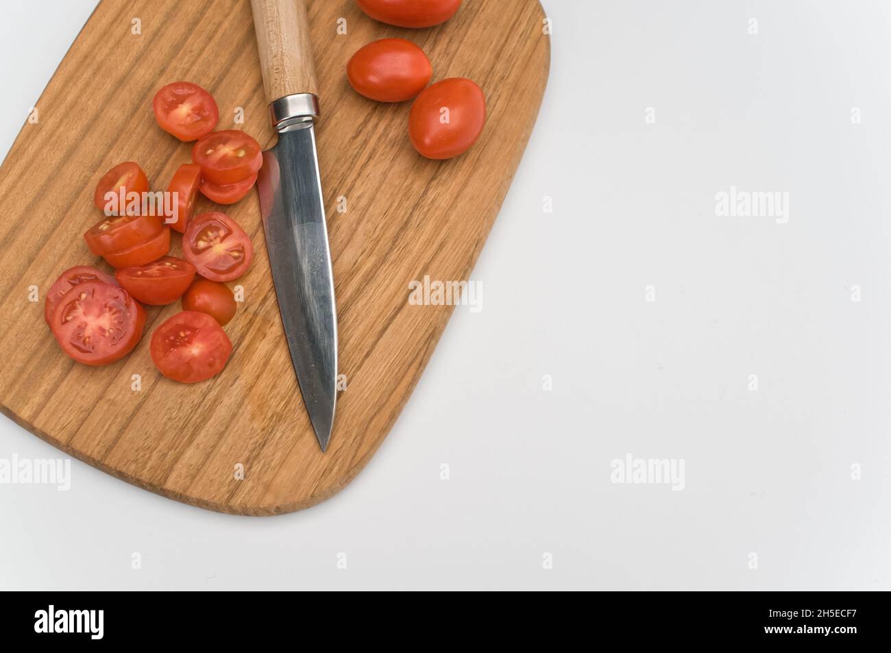datterini tomatoes and knife on a wooden chopping board on a white ...
