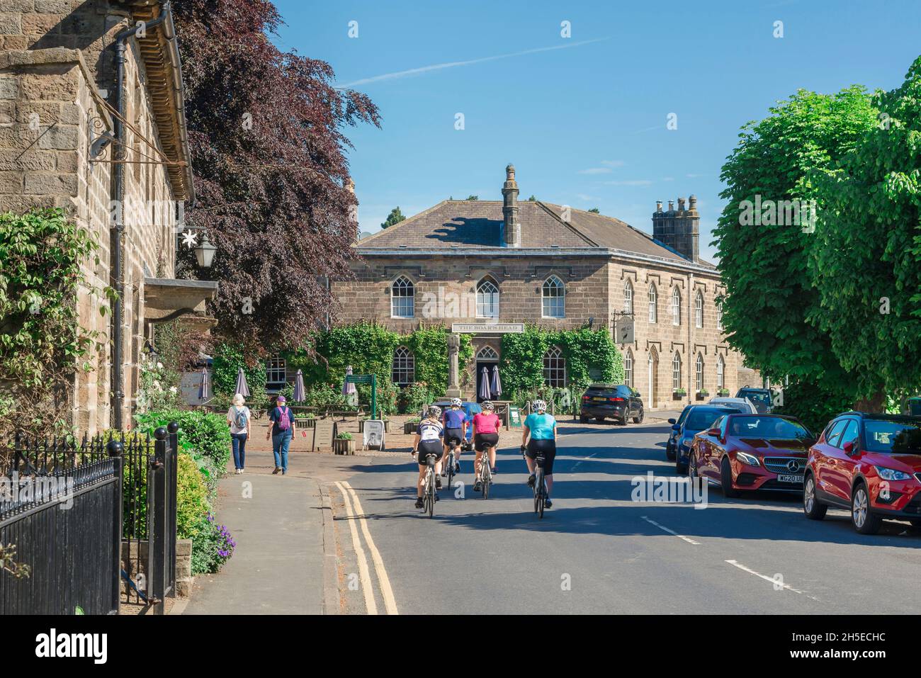 Ripley Yorkshire, view in summer of cyclists riding through Main Street in the scenic village of Ripley with the Boars Head Hotel directly ahead, UK Stock Photo