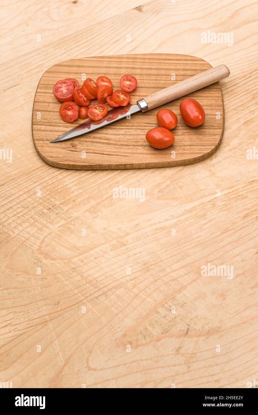 datterini tomatoes and knife on a wooden chopping board on a rustic ...