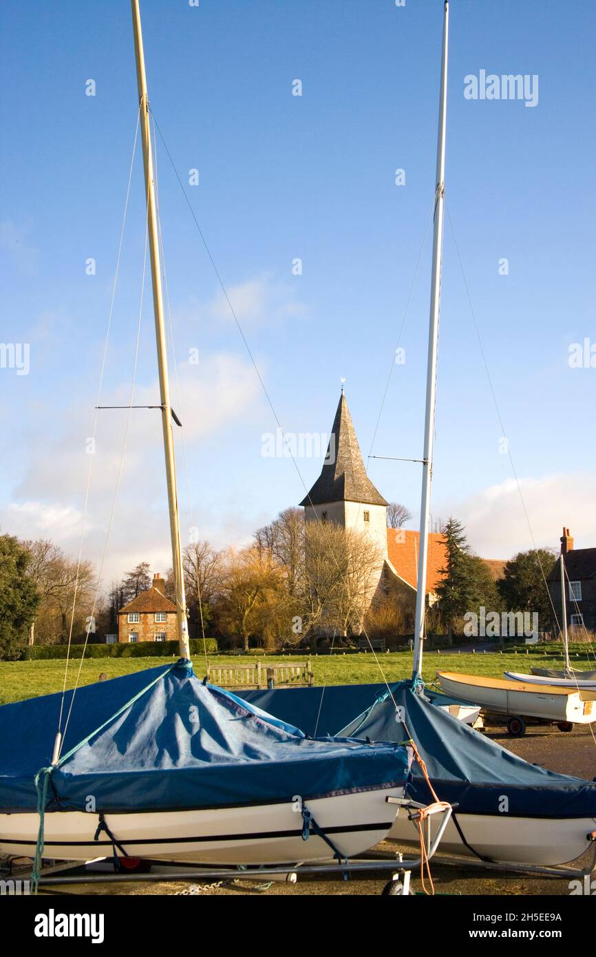 the masts of two sailing boats framing holy trinity church in bosham west sussex Stock Photo