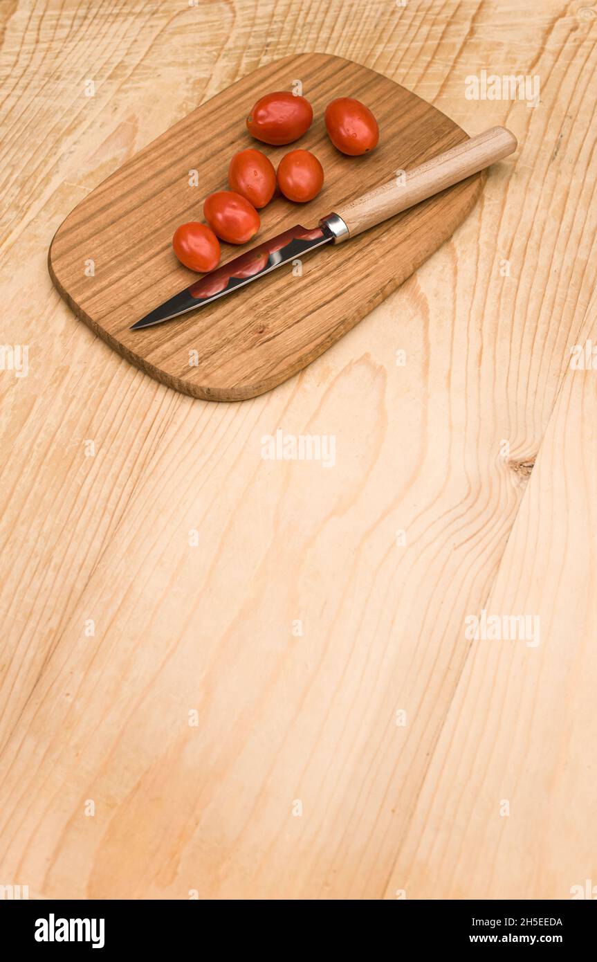 datterini tomatoes and knife on a wooden chopping board on a rustic ...
