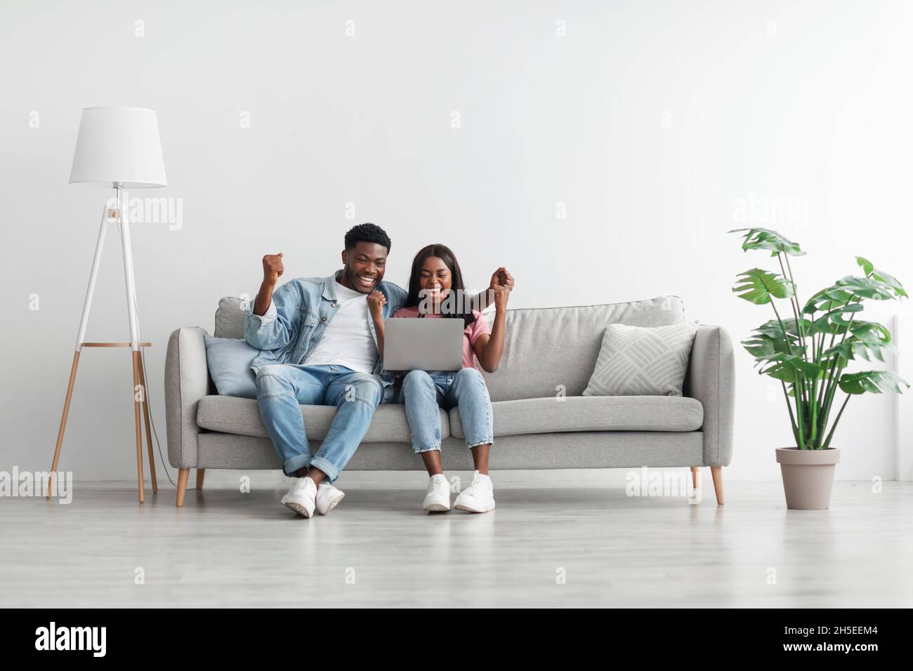 African american couple using laptop, celebrating win Stock Photo - Alamy