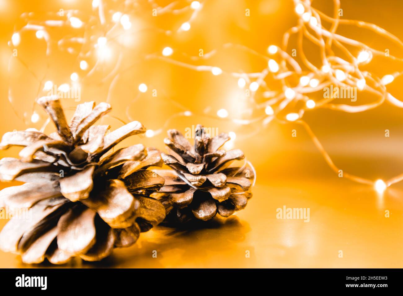 Christmas cones on a golden background with lights. Christmas background. 2022 Stock Photo