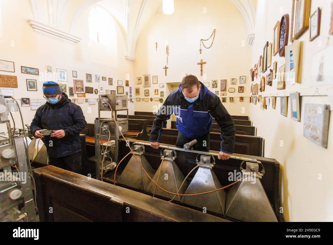 09 November 2021, Baden-Wuerttemberg, Rastatt: André Matzke (l-r) and Heiko Richter attach horn-shaped antennas for microwave irradiation to church pews. The Einsiedeln Chapel is one of the Baroque buildings built under Margravine Sibylla Augusta at the beginning of the 18th century in her residence in Rastatt. The pews from the time of construction are infested with pests. Microwave technology is to be used to combat the infestation without using poison and damaging the historic substance. Photo: Philipp von Ditfurth/dpa Stock Photo