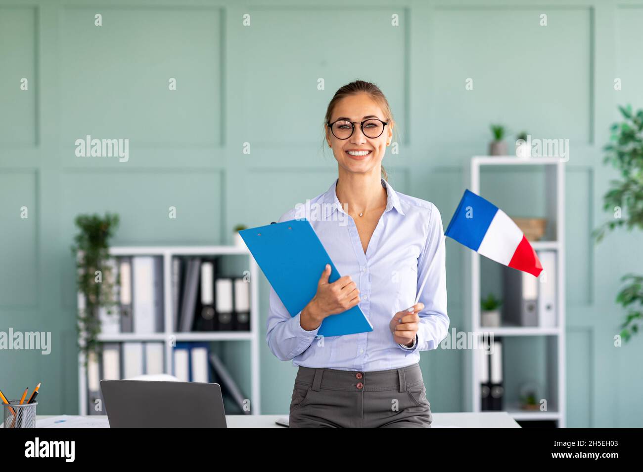 Foreign languages tutoring. Happy teacher holding flag of France and